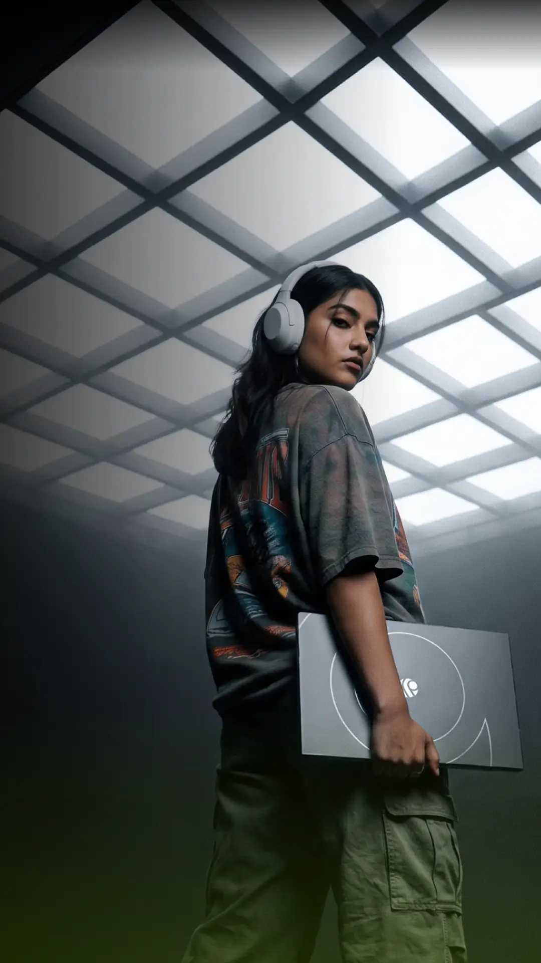 Primebook customer support — woman with headphones holding a Primebook laptop under a skylight